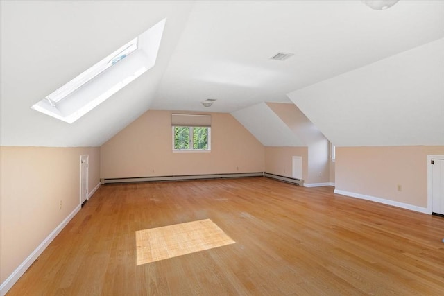 additional living space featuring visible vents, light wood-style floors, lofted ceiling with skylight, and baseboards