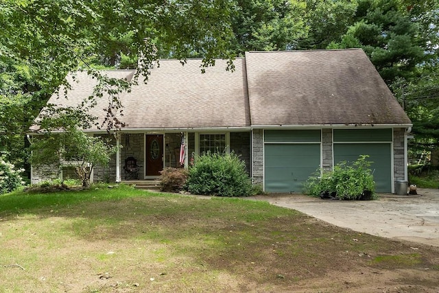 cape cod home featuring a garage, a shingled roof, concrete driveway, stone siding, and a front yard