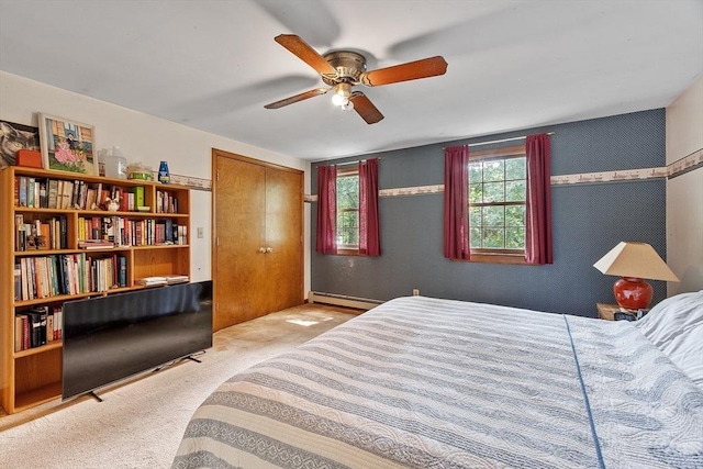 bedroom featuring carpet floors, a closet, baseboard heating, and a ceiling fan