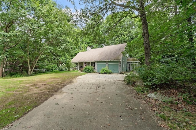 view of front facade with driveway, a chimney, an attached garage, and a front yard