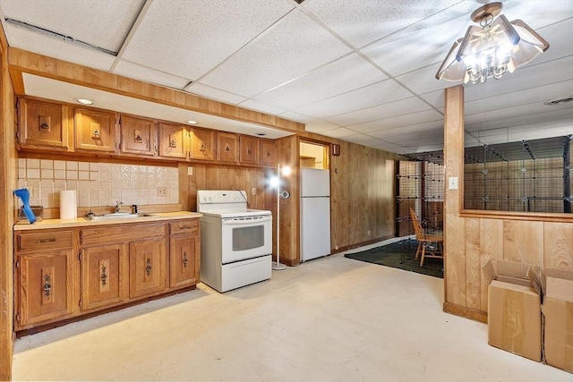 kitchen with concrete floors, white appliances, brown cabinets, and wood walls