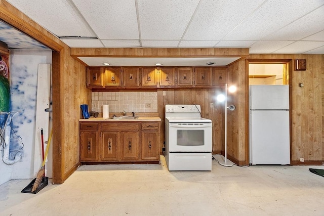 kitchen featuring white appliances, wooden walls, brown cabinets, concrete floors, and a sink