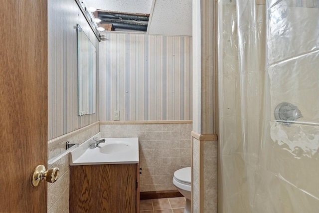 bathroom featuring tile patterned flooring, a wainscoted wall, a shower with shower curtain, vanity, and tile walls