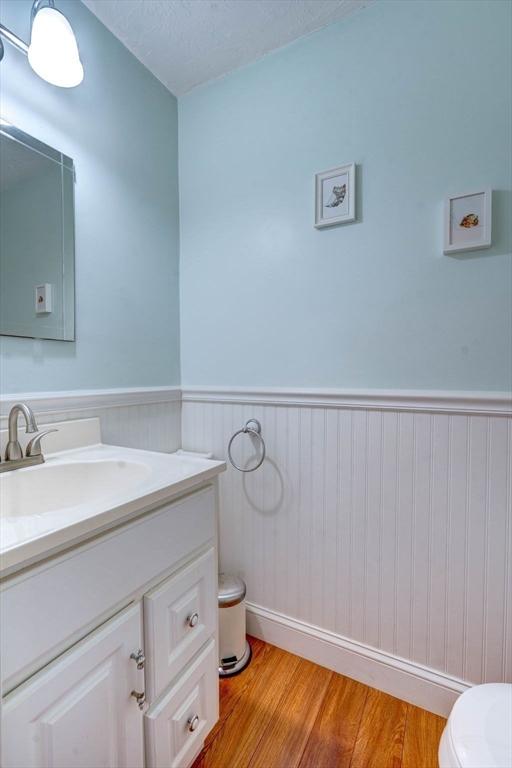 25 Church St Unit 2, Weymouth, MA 02189 - half bathroom with toilet, wainscoting, vanity, and wood finished floors