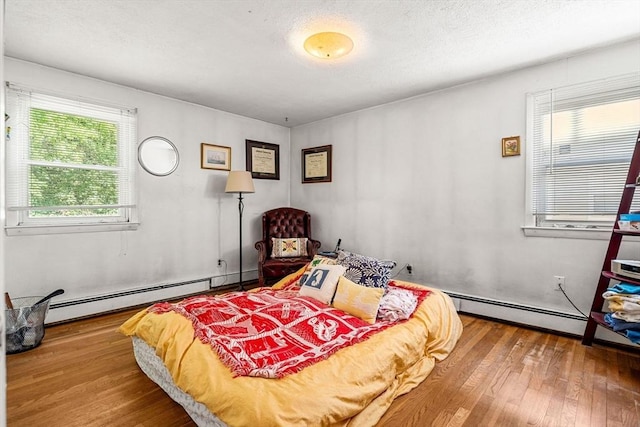 bedroom with wood-type flooring and baseboard heating