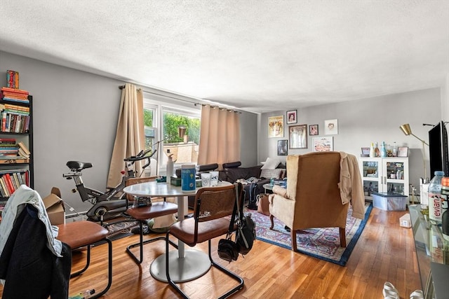 living area featuring a textured ceiling, light wood-style flooring, and a baseboard heating unit
