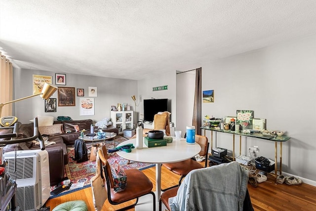 dining area featuring a textured ceiling, wood finished floors, and baseboards