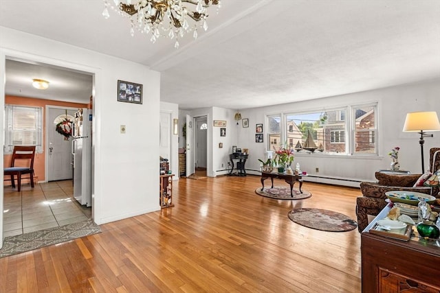 living room featuring light wood-style floors, a chandelier, a baseboard heating unit, and baseboards