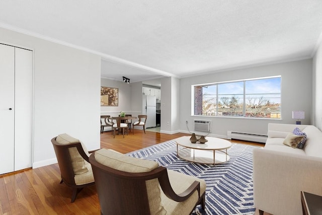 living room with crown molding, a baseboard radiator, a wall unit AC, and light hardwood / wood-style flooring