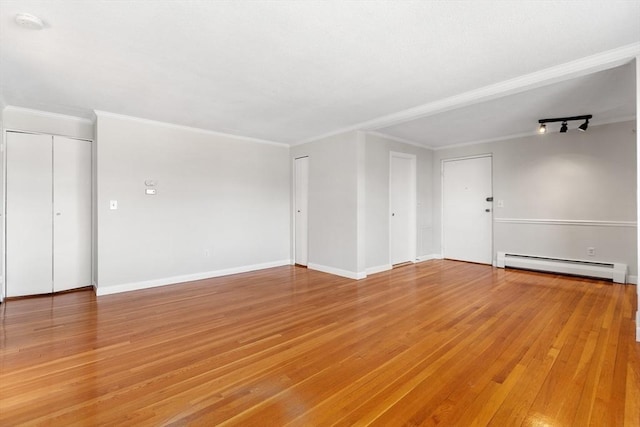 empty room with crown molding, hardwood / wood-style flooring, and a baseboard radiator