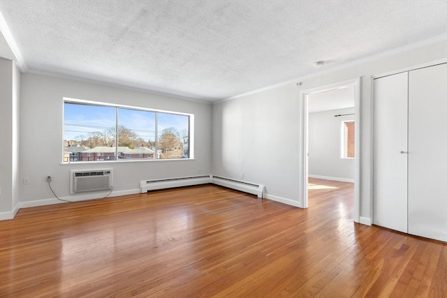 interior space with crown molding, a wall mounted air conditioner, a textured ceiling, light hardwood / wood-style floors, and a baseboard heating unit