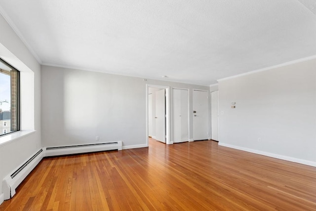 empty room featuring ornamental molding, wood-type flooring, and a baseboard radiator