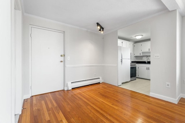 unfurnished dining area with a baseboard radiator, ornamental molding, sink, and light hardwood / wood-style flooring