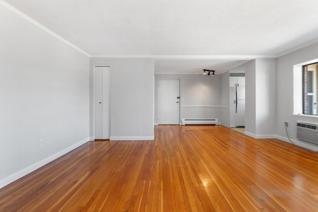 empty room with hardwood / wood-style flooring, a baseboard radiator, an AC wall unit, and crown molding