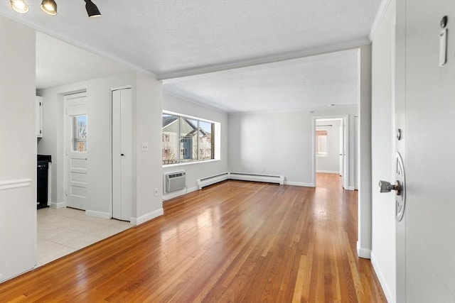 unfurnished living room with baseboard heating, light hardwood / wood-style floors, and a wall unit AC