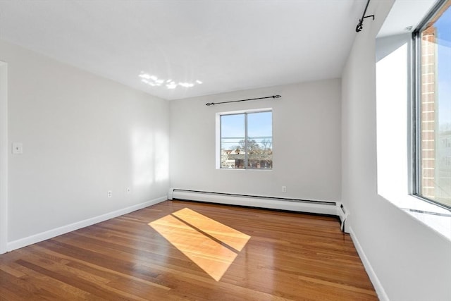 empty room featuring hardwood / wood-style flooring and a baseboard radiator