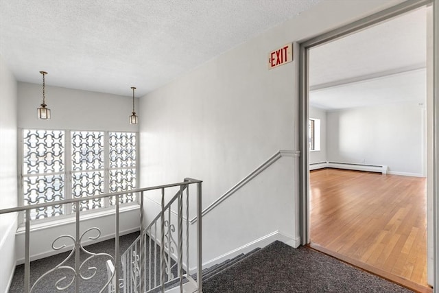 hall with a textured ceiling and a baseboard heating unit