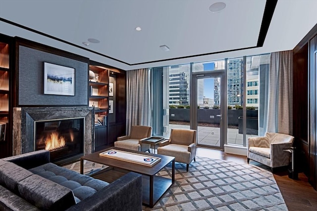 living room with built in shelves, a wall of windows, and wood-type flooring