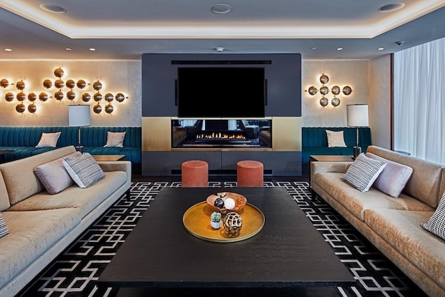 home theater room with a raised ceiling and a fireplace