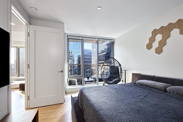 bedroom with light wood-type flooring and a wall of windows