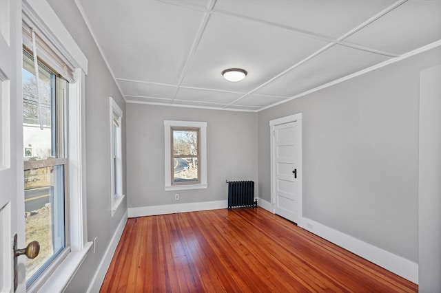 spare room featuring radiator, wood-type flooring, and coffered ceiling