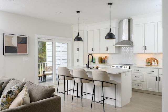 20 Howland Trl Unit 10, Hanson, MA 02341 - kitchen with wall chimney range hood, open floor plan, a breakfast bar area, backsplash, and light wood-style flooring