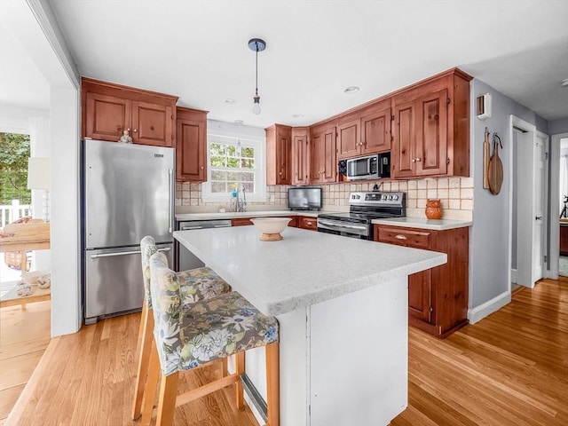 125 Grove St, Norwell, MA 02061 - kitchen featuring stainless steel appliances, light countertops, light wood-type flooring, and pendant lighting