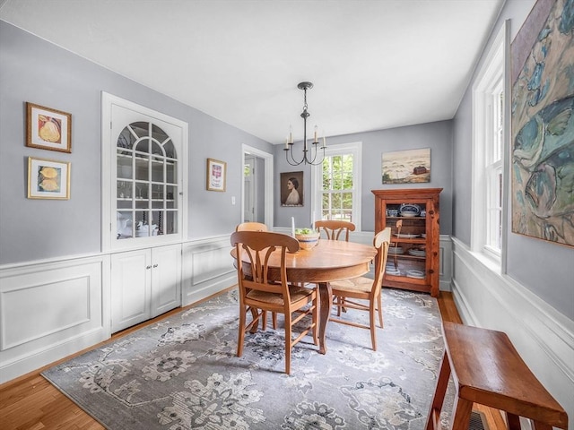 125 Grove St, Norwell, MA 02061 - dining space with a chandelier, a wainscoted wall, wood finished floors, and a decorative wall