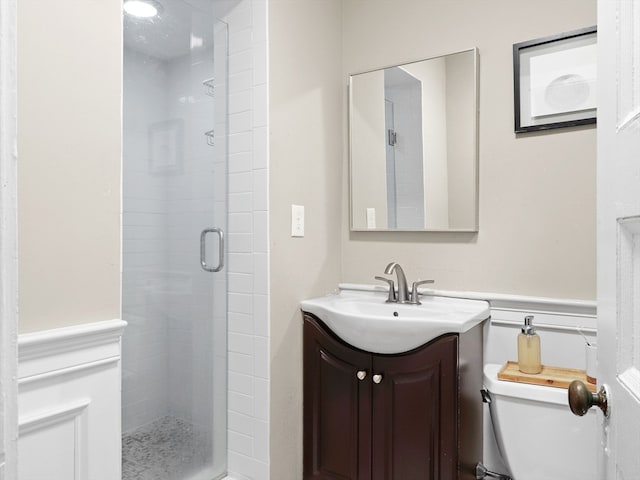 bathroom with vanity, toilet, and a shower with door