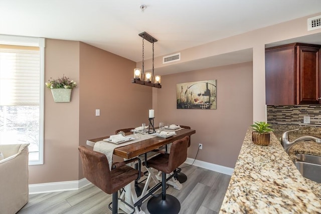 dining space featuring an inviting chandelier, sink, and light hardwood / wood-style flooring