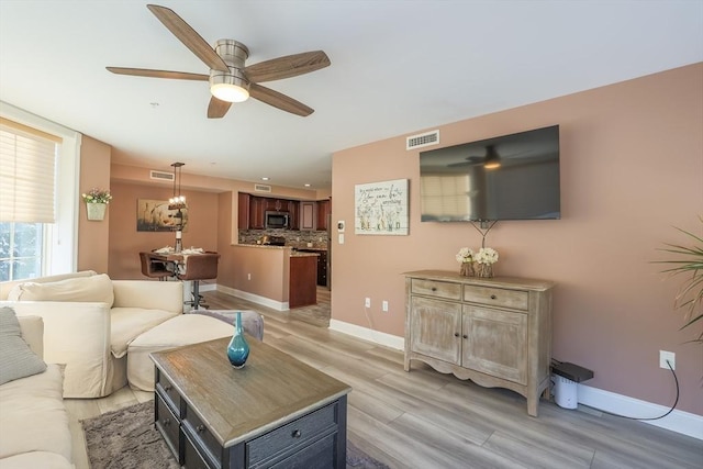 living room with light hardwood / wood-style floors and ceiling fan