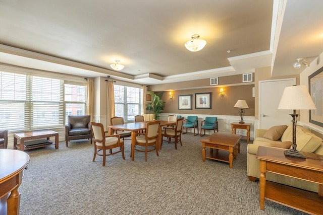 carpeted living room with ornamental molding and a raised ceiling