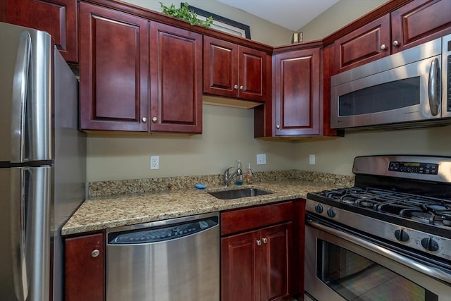 kitchen featuring stainless steel appliances, light stone countertops, and sink