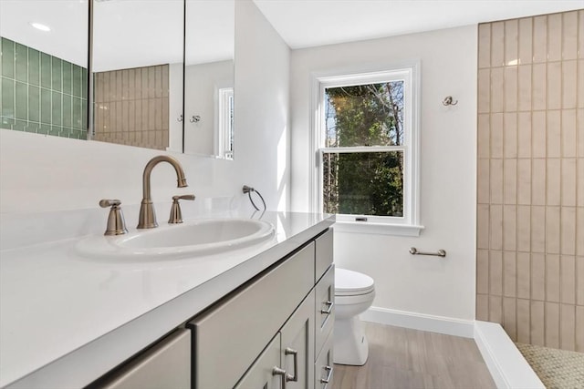 506 Woods Hole Rd, Falmouth, MA 02543 - bathroom with vanity, baseboards, toilet, wood finished floors, and a tile shower