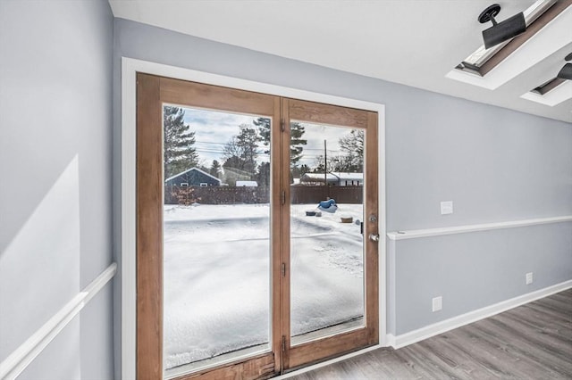 entryway with a skylight, baseboards, and wood finished floors