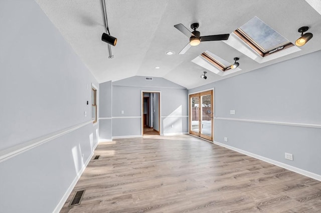 bonus room featuring vaulted ceiling with skylight, visible vents, baseboards, ceiling fan, and light wood-style flooring