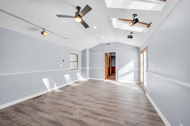 unfurnished room featuring lofted ceiling with skylight, visible vents, baseboards, and wood finished floors