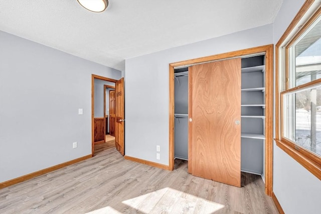 unfurnished bedroom with a closet, multiple windows, and wood finished floors