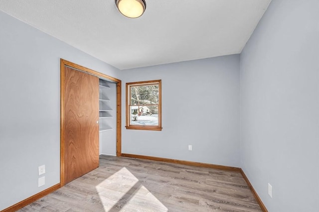 unfurnished bedroom with a closet, baseboards, and wood finished floors