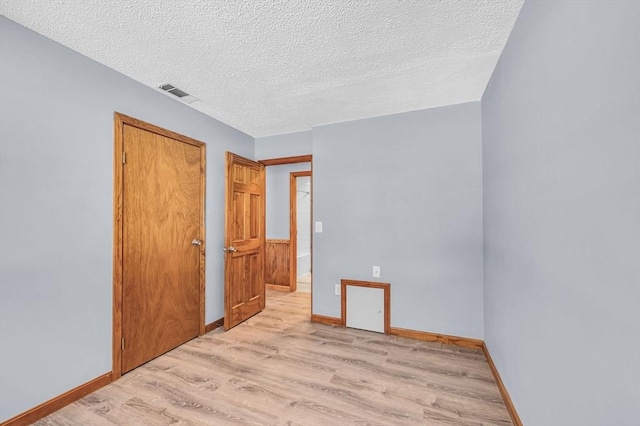 unfurnished bedroom with light wood finished floors, a closet, visible vents, a textured ceiling, and baseboards