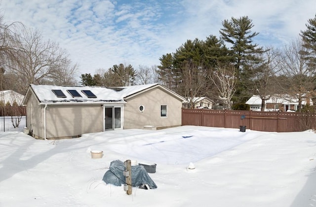 snow covered house with fence and solar panels