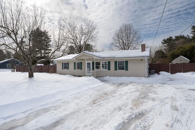 ranch-style home with a chimney, fence, and cooling unit