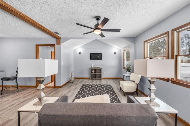 living area with ceiling fan, a textured ceiling, wood finished floors, visible vents, and vaulted ceiling