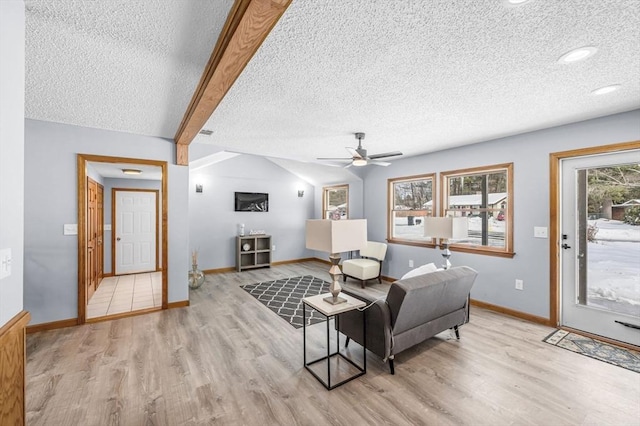 living room featuring light wood-type flooring, vaulted ceiling with beams, baseboards, and a textured ceiling