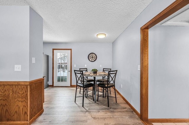 dining space with a textured ceiling, baseboards, and wood finished floors