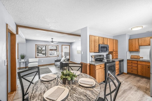 kitchen with a textured ceiling, appliances with stainless steel finishes, light wood-type flooring, tasteful backsplash, and brown cabinetry