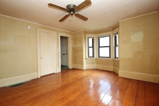 unfurnished room featuring a ceiling fan, baseboards, ornamental molding, and light wood-type flooring