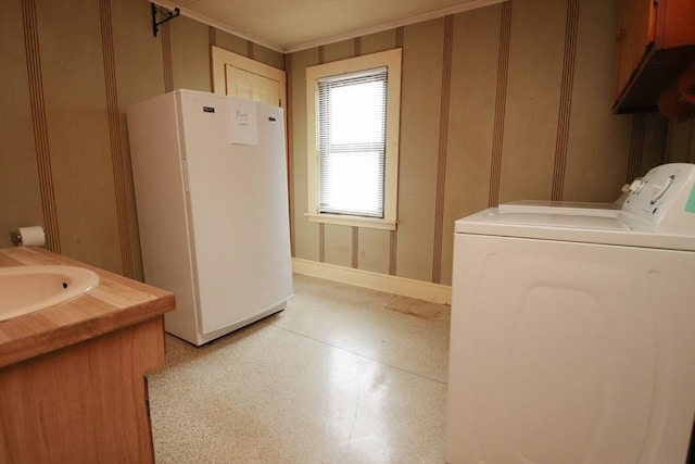 laundry area with crown molding, laundry area, a sink, and washer and clothes dryer