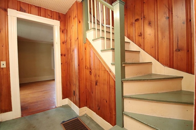 stairs with baseboards, wood walls, and carpet floors