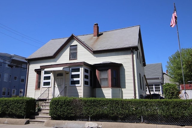 bungalow featuring a shingled roof and a chimney